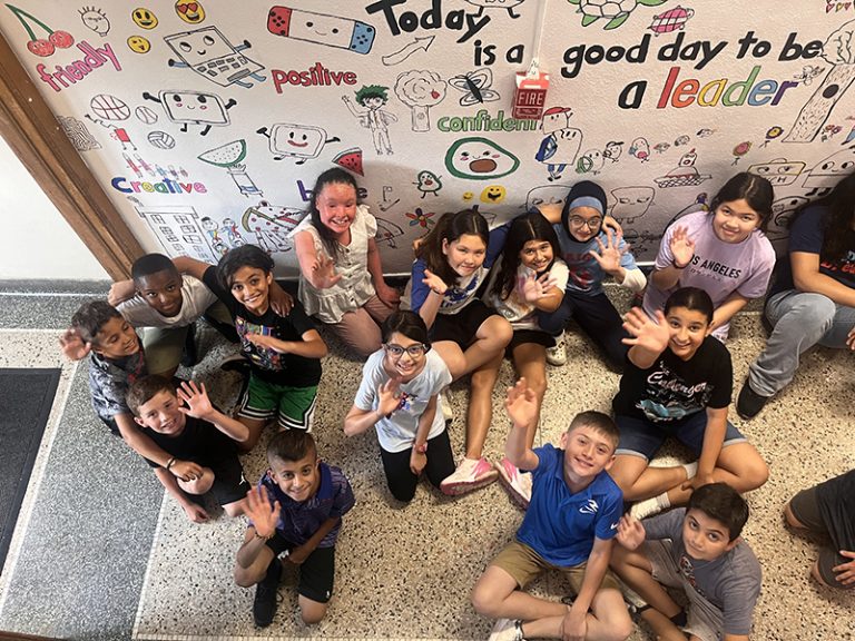 Students in the Lindbergh Elementary 2025 Summer Discovery Program pose in front of a mural they are creating.